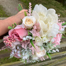 a brides wedding bouquet of artificial flowers  in shades of ivory & pink