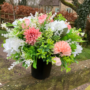 A graveside flower arrangement in black pot