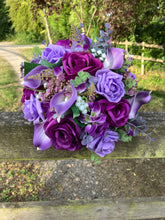 An artificial faux silk wedding bouquet of purple flowers