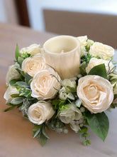 A table centrepiece of ivory flowers, foliage & led candle