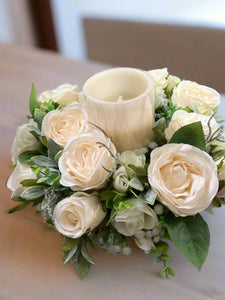 A table centrepiece of ivory flowers, foliage & led candle