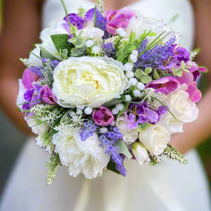 A brides bouquet featuring lilac, lavender and ivory artificial flowers