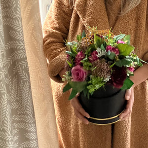 A flower arrangement in black hat box