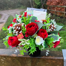 a christmas grave side memorial arrangement with red artificial roses