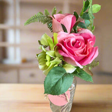 A posy of artificial pink and green flowers in glass bud vase