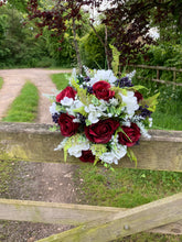 A wedding bouquet of artificial silk burgundy & ivory flowers, foliage & berries