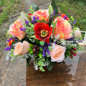 a grave pot with flowers featuring orange and purple artificial silk blooms