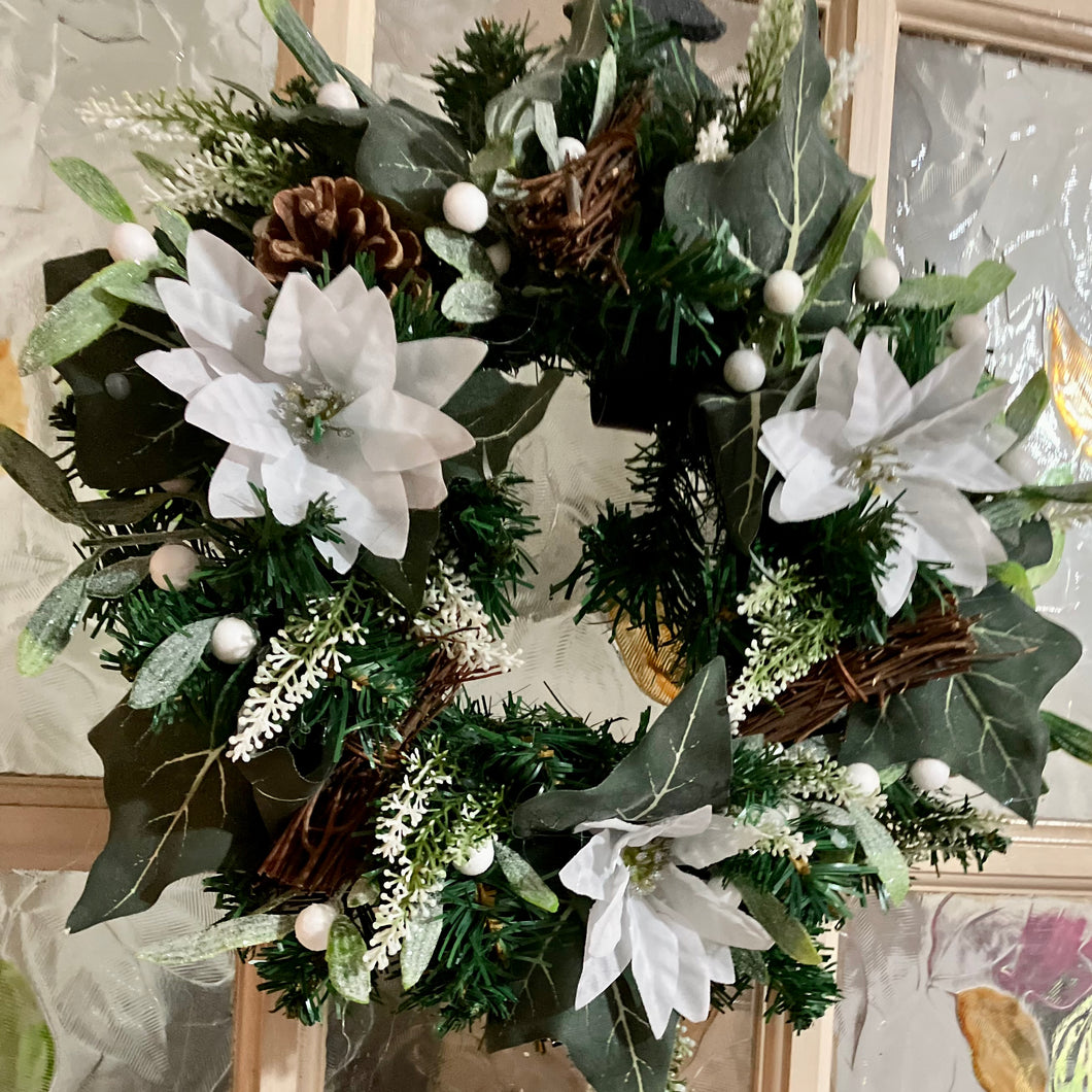 an artificial pine christmas wreath with white poinsettia
