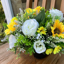 a grave side pot with flowers in shades of yellow and cream
