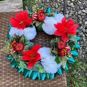 a memorial christmas wreath featuring baubles, cones and poinsettia