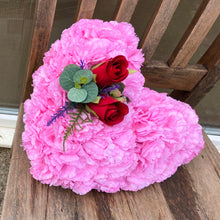 a memorial heart of artificial silk roses and carnations in shades of pink & red