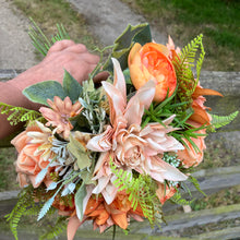 A brides bouquet featuring dahlia, ranunculas and roses