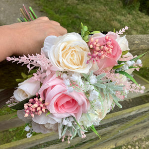 a brides wedding bouquet of artificial flowers  in shades of ivory & pink