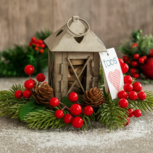 Decorative lantern with red berries and a 'tobs' tag on a textured surface.