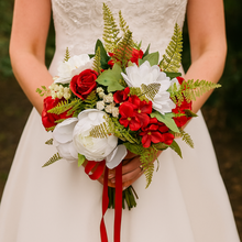 Bouquet of red and white flowers held by a person wearing a white dress.