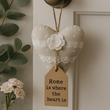 Heart-shaped decorative item with a tag on a door, accompanied by flowers and greenery.