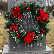 An artificial pine christmas wreath with holly and poinsettia