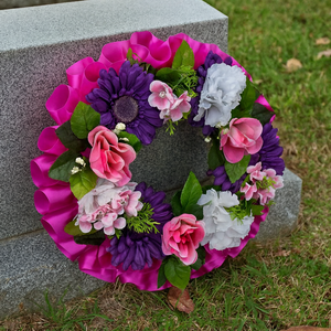 a memorial wreath of artificial silk roses and gerbera in shades of pink
