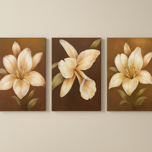 Three floral paintings of beige flowers on brown backgrounds hanging on a wall.