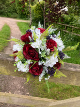 A wedding bouquet of artificial silk burgundy & ivory flowers, foliage & berries