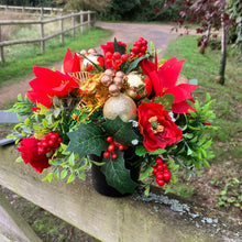 a christmas grave side memorial pot with red artificial flower arrangement