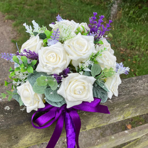 A wedding bouquet of artificial ivory roses & lavender flowers