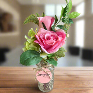 A posy of artificial pink and green flowers in glass bud vase
