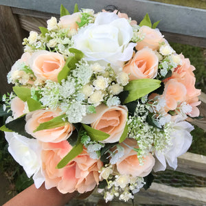 A wedding bouquet featuring silk flowers in shades of ivory and peach