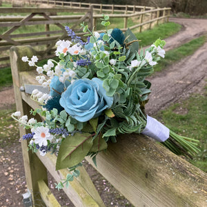 A wedding bouquet of white and teal flowers and foliage