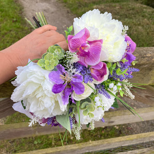 A brides bouquet featuring lilac, lavender and ivory artificial flowers