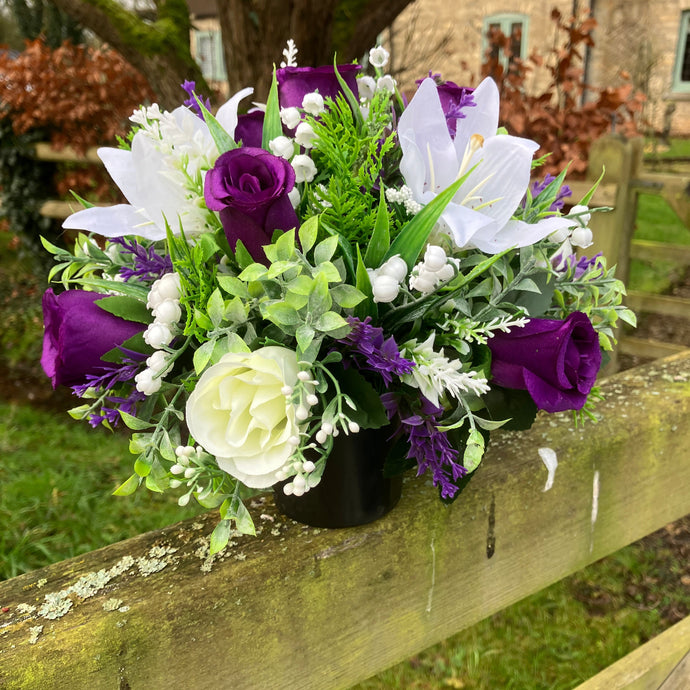 a grave side pot with flowers in shades of purple and cream