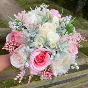 a brides wedding bouquet of artificial flowers  in shades of ivory & pink