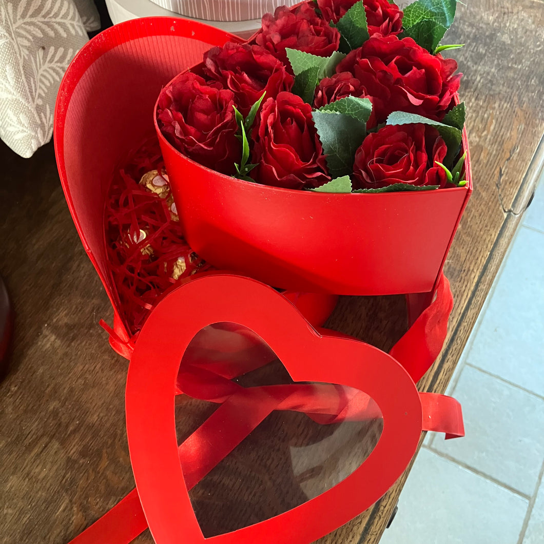 A Flower arrangement of red roses and ferrero rocha in red heart box
