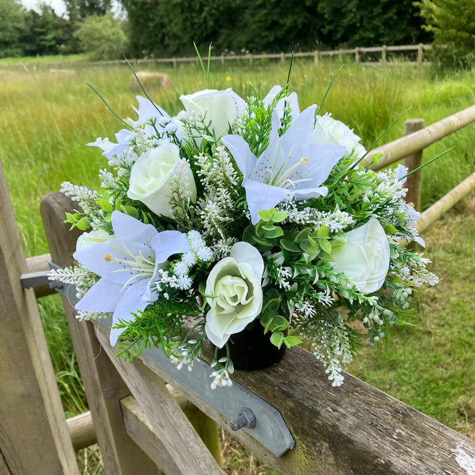 Ivory memorial flowers arranged in black plastic pot