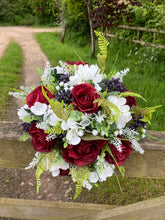 A wedding bouquet of artificial silk burgundy & ivory flowers, foliage & berries