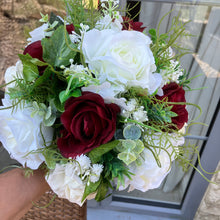 A brides bouquet of deep burgundy and ivory faux flowers