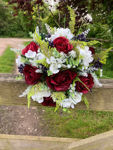 A wedding bouquet of artificial silk burgundy & ivory flowers, foliage & berries