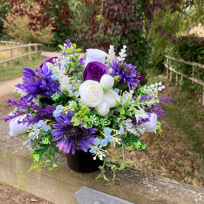 a grave pot with white artificial silk cornflowers and rose blooms