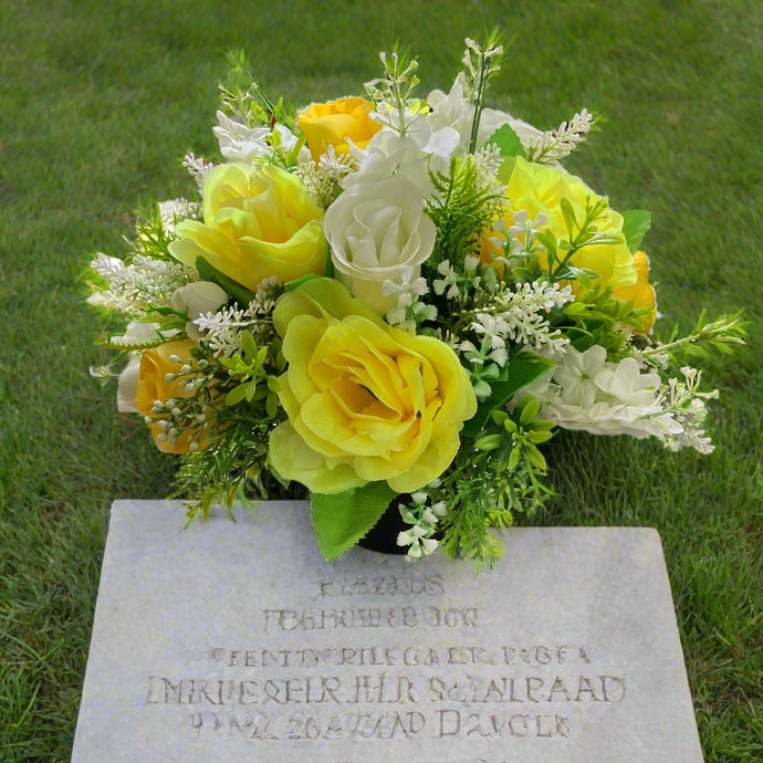 a grave side pot with flowers in shades of yellow and cream