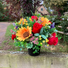 A graveside flower arrangement in black pot