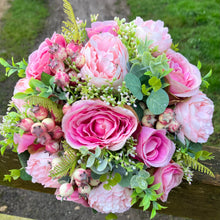 A wedding bouquet featuring pink roses and ranaculus