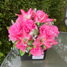flower arrangement of artificial roses and lilies in black box