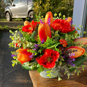 An artificial flower arrangement of orange and red flowers