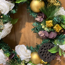 An artificial pine christmas wreath with pale gold and ivory decorations