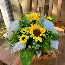 a grave side pot with flowers in shades of yellow and cream