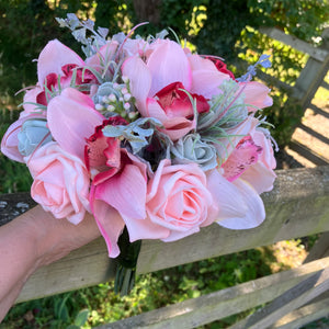 A wedding bouquet of coral and grey artificial roses and orchids
