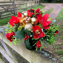 a christmas grave side memorial pot with red artificial flower arrangement