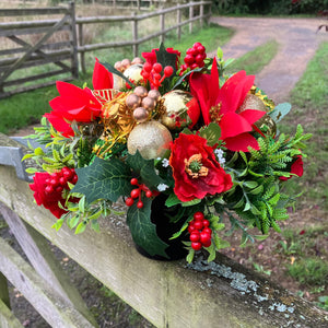 a christmas grave side memorial pot with red artificial flower arrangement