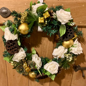 An artificial pine christmas wreath with pale gold and ivory decorations