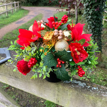 a christmas grave side memorial pot with red artificial flower arrangement
